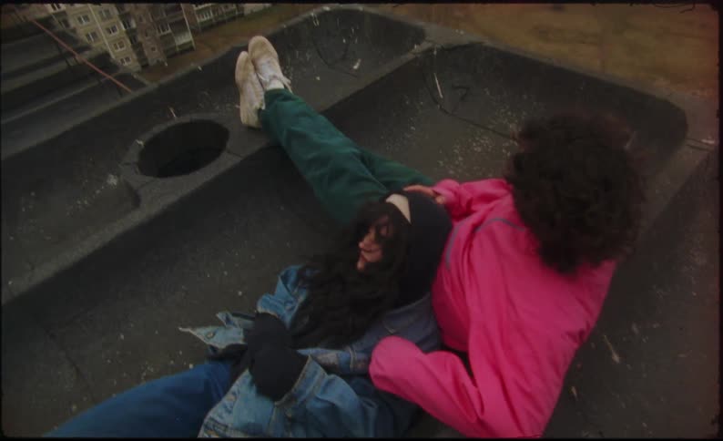 Couple lie down on roof overlooking apartment buildings
