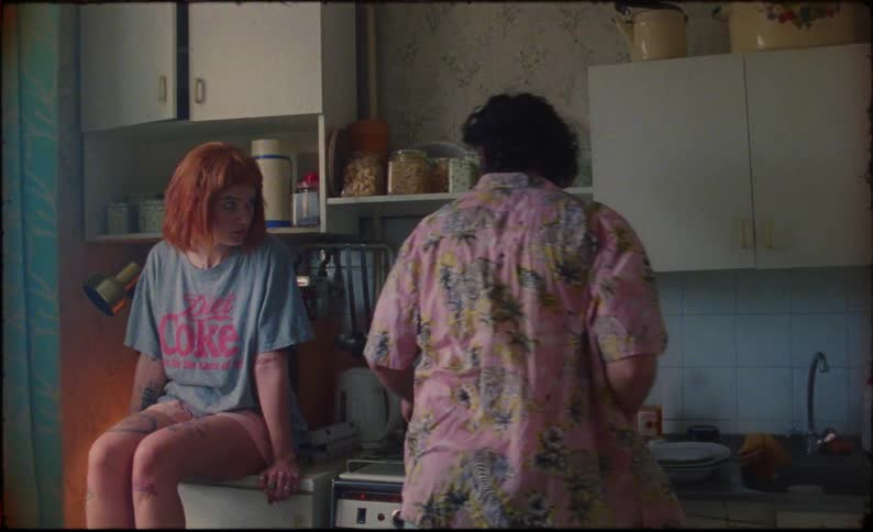 A woman sits on the counter and watches as her partner cooks