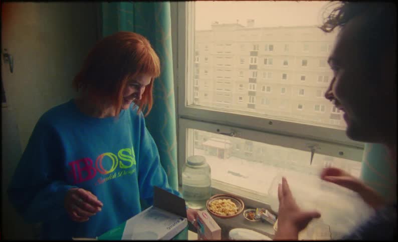 A man and woman tease and play around while unboxing a new coffee maker in their small apartment