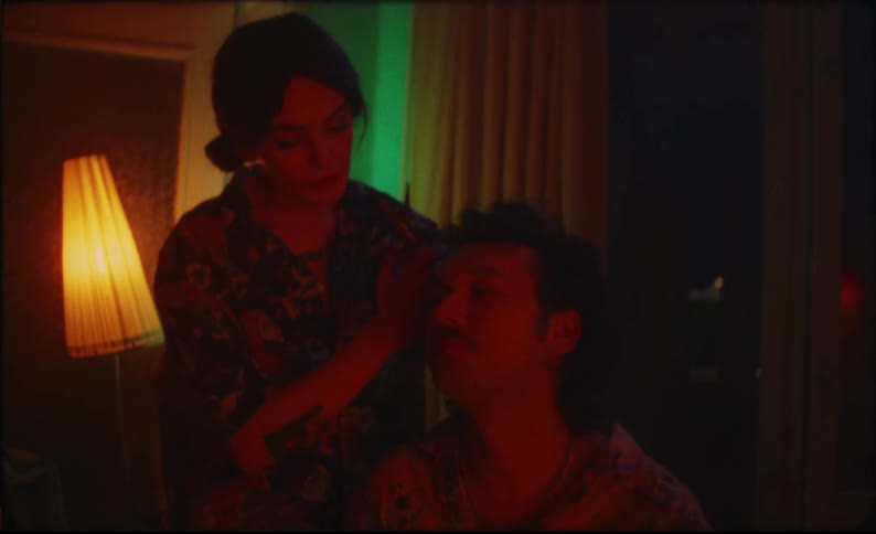 A woman kisses her boyfriend while styling his hair