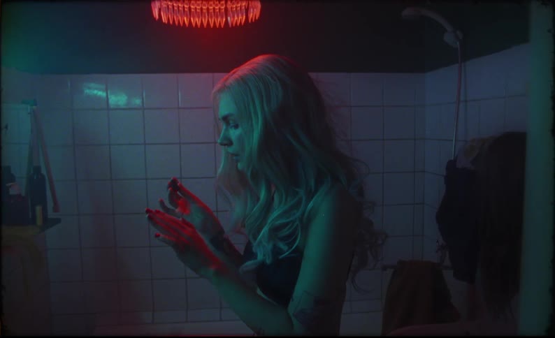 A woman blows on her nails after applying polish in a dark bathroom