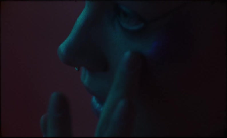 A woman is in a dark room and putting on makeup