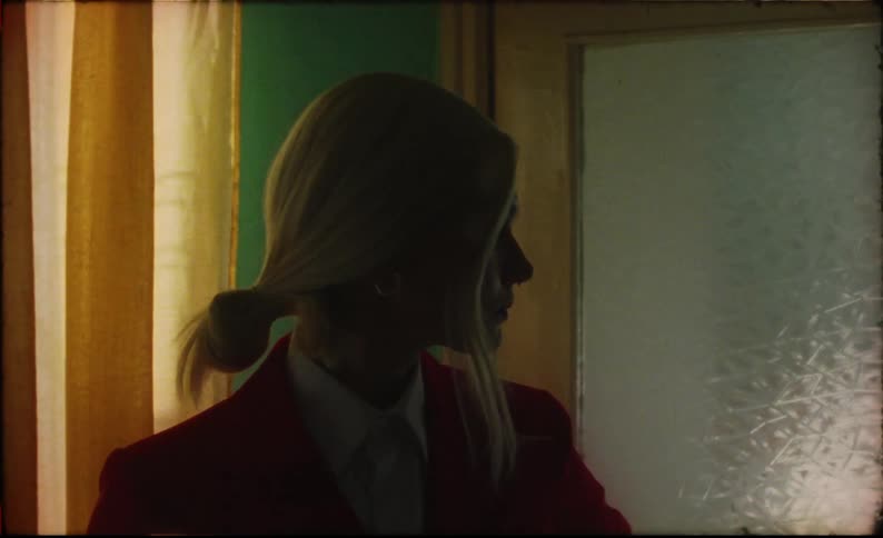 A woman standing posed in the kitchen then walks out the door and pauses