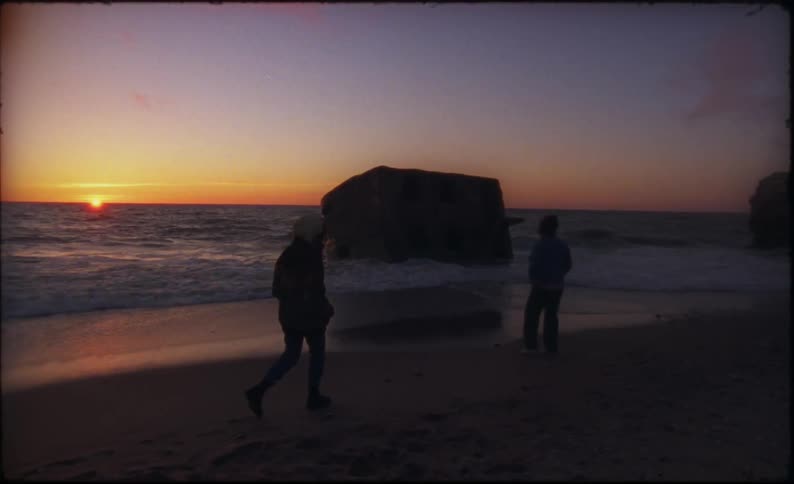 Two people meeting up at a beach at dusk