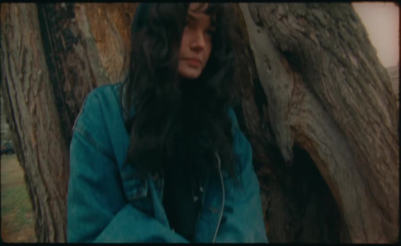 A girl sits on the tree trunk