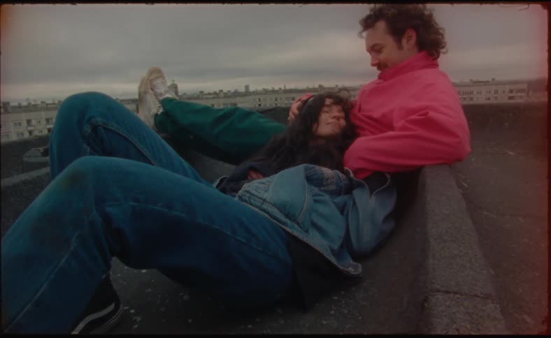 A woman smiles while lying in her boyfriends lap on the rooftop of a building
