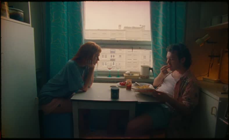 A man and woman sit at a small breakfast table as the man eats