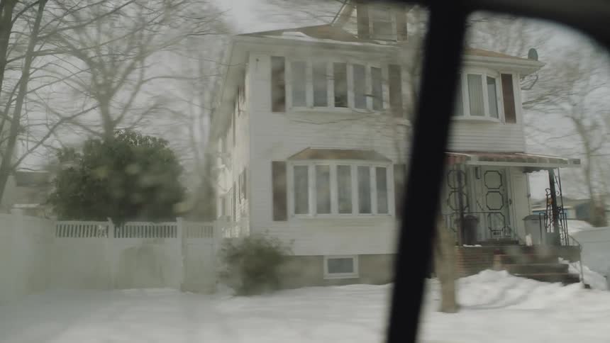 A car is driving through a residential area during winter