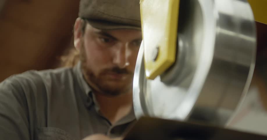 Man moves thins sheet of metal between metal disks to shape