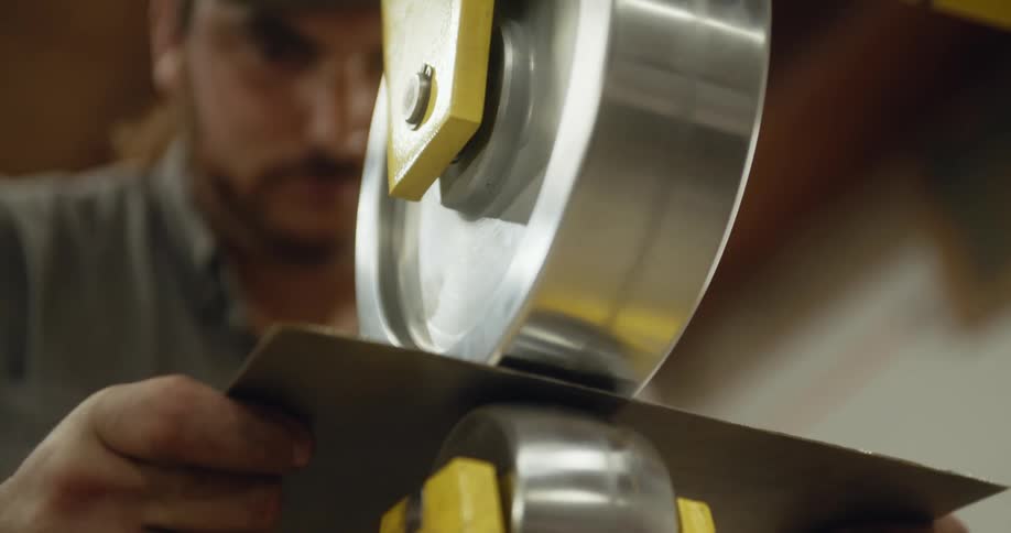 A man uses a wheeling machine to hand shape sheet metal
