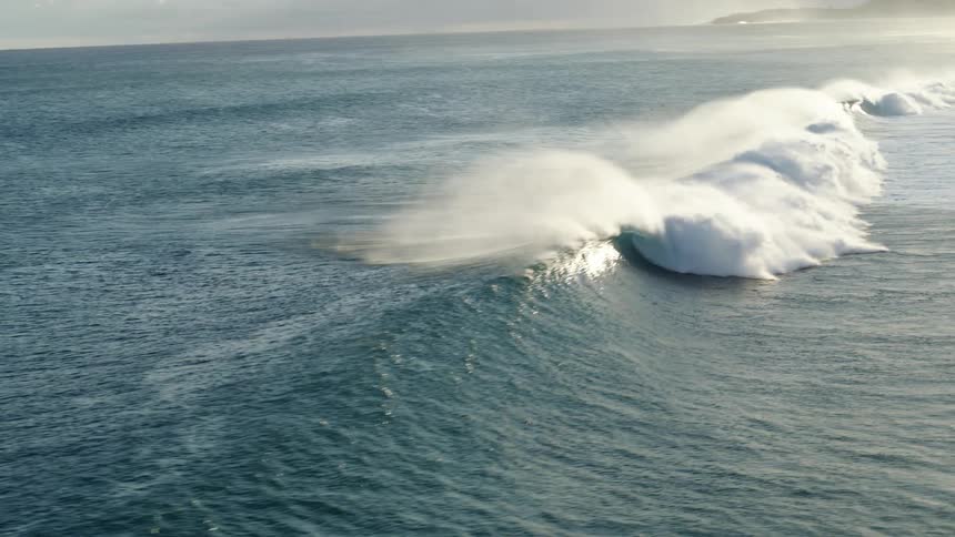 People are floating in the water as a large wave rolls in splashing over them