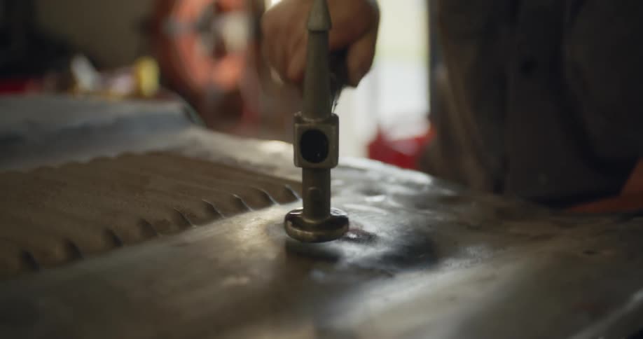 A man in a workshop hammers on heated metal