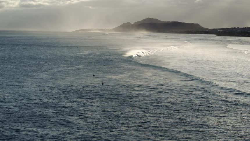 Aerial view of two people in the ocean as waves roll in to the shore