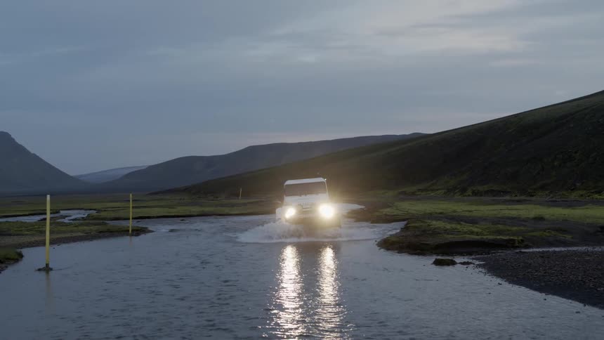 A car is driving off road through water