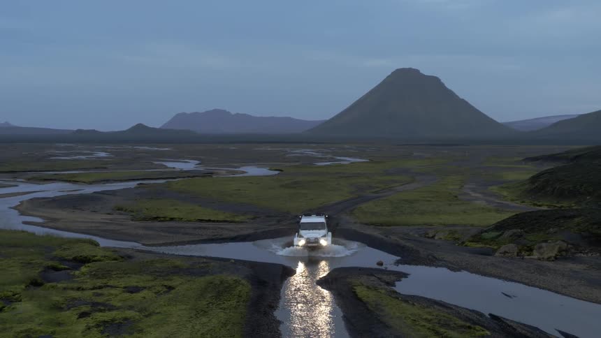 A vehicle driving off road crosses a river