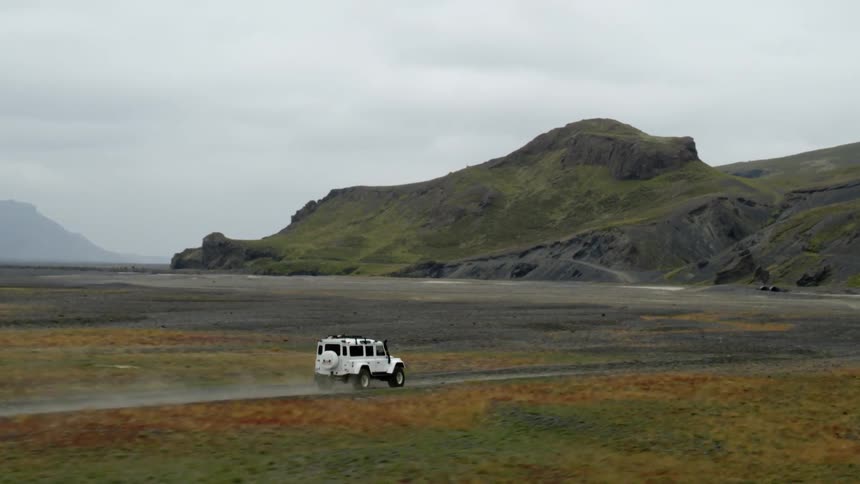 A vehicle driving across the land towards hills