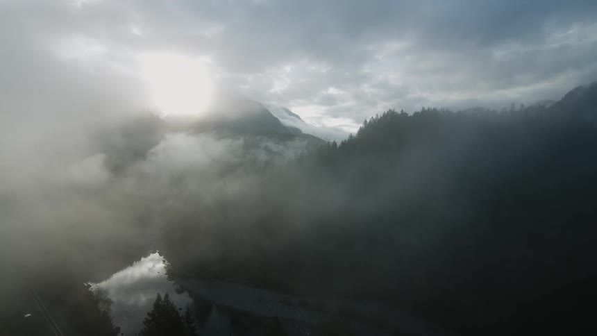 Sunlight peaks through dense clouds over a forest