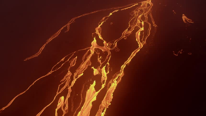 Lava is flowing in streams from the cone of a volcano