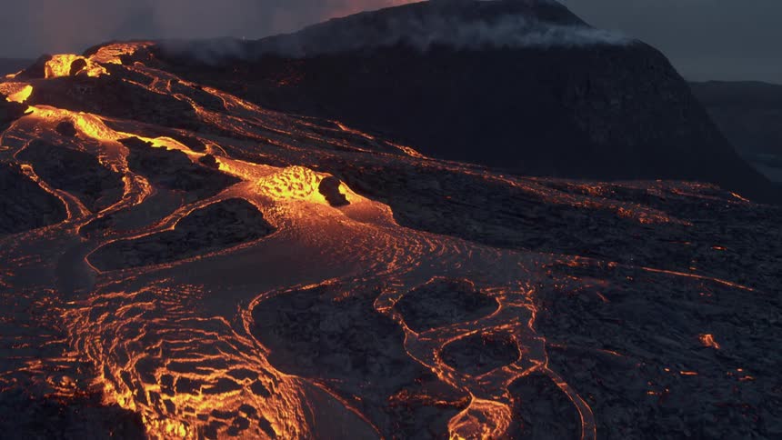 Burning lava flows down the side of an erupting volcano