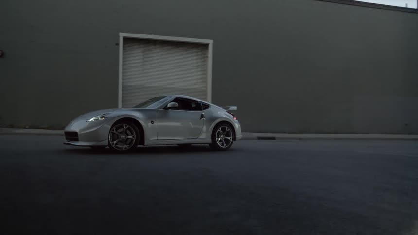 A car drifts in a lot by a building