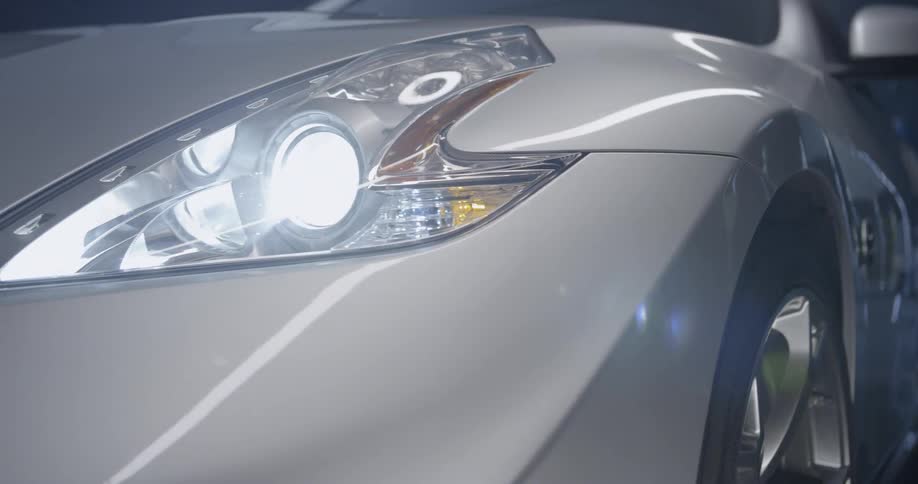 A silver car is very shiny with bright headlights