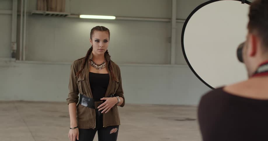 Fashion model poses for photographer in large concrete floored room