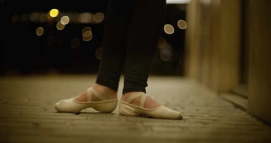 A girl is practicing a ballet dance at night