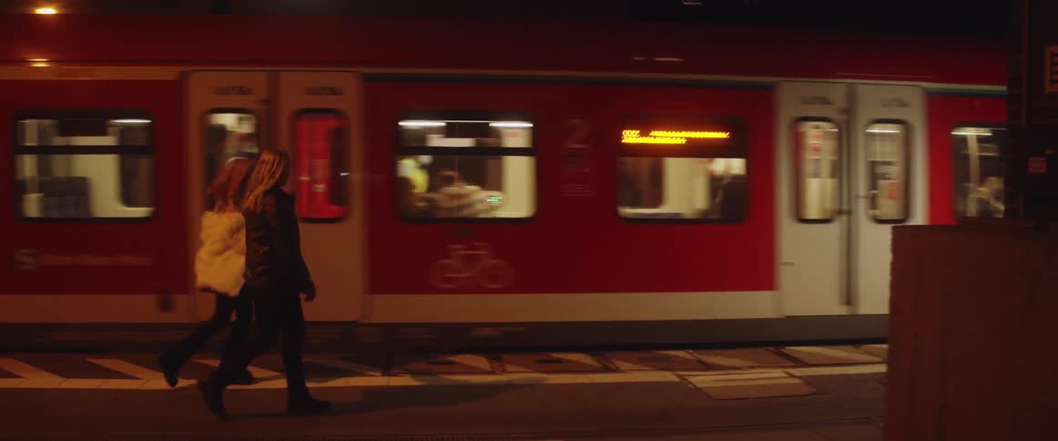 Two girls are walking in the subway as a train is passing and then they run