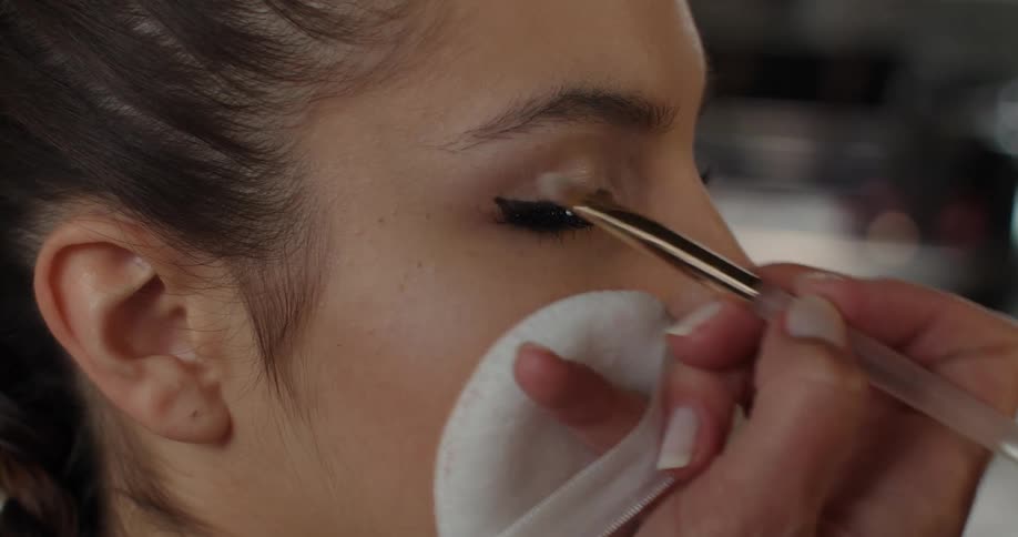 A woman puts eye make up on