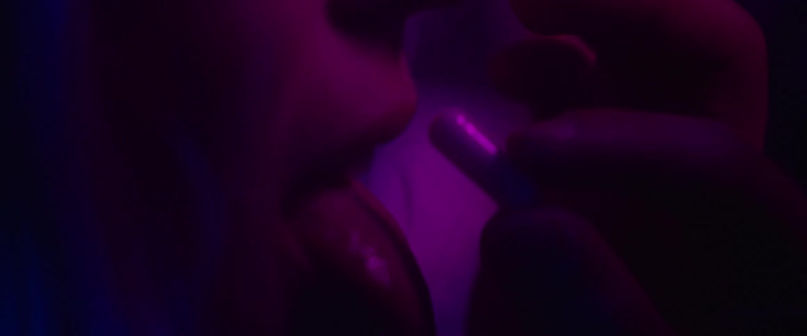 A person puts a pill in a womans mouth while they dance in a club