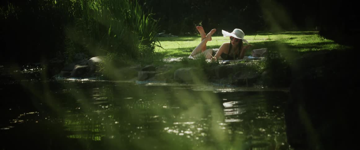 Woman lies on her stomach on shore in the shade