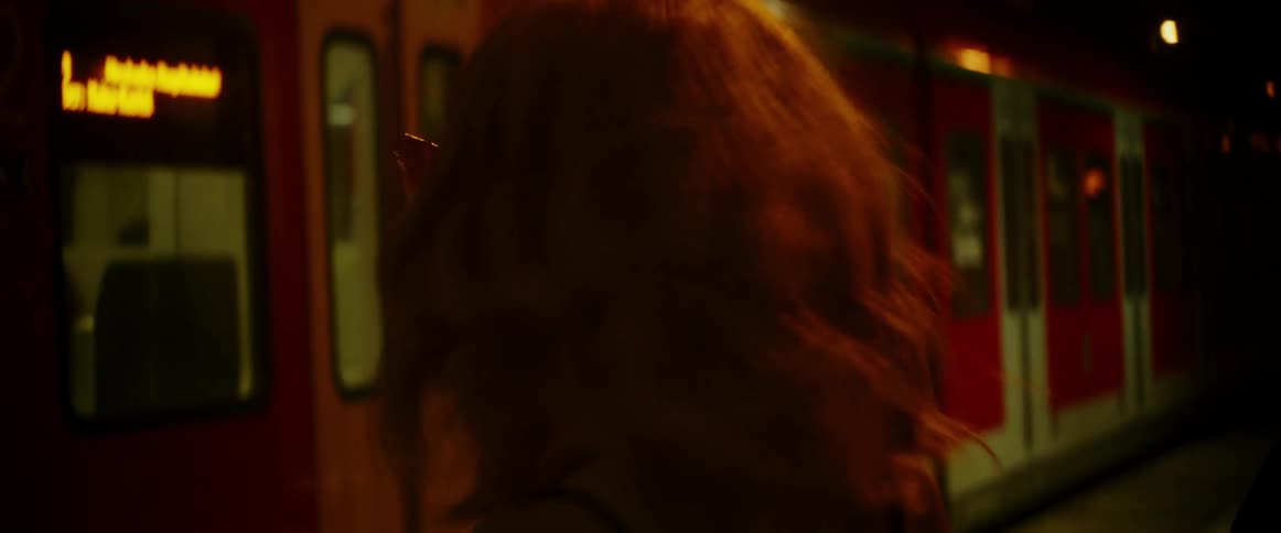 A woman walking next to a train at night