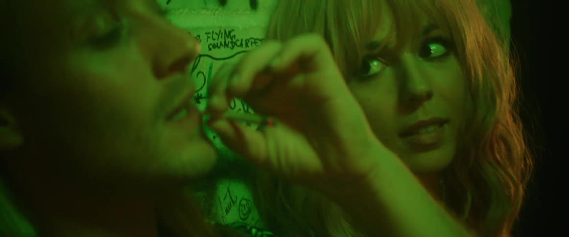A woman sits next to a man who is smoking a cigarette and then looks over at him with a smile