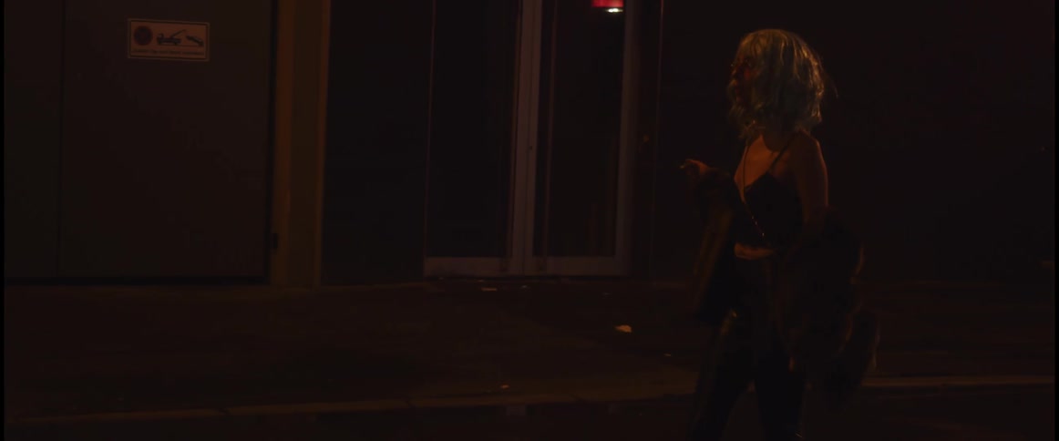 A woman walks alone down a city street at night