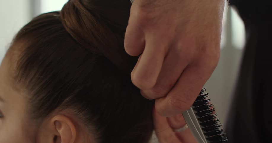 A hairstylist puts a clients hair into a sleek bun