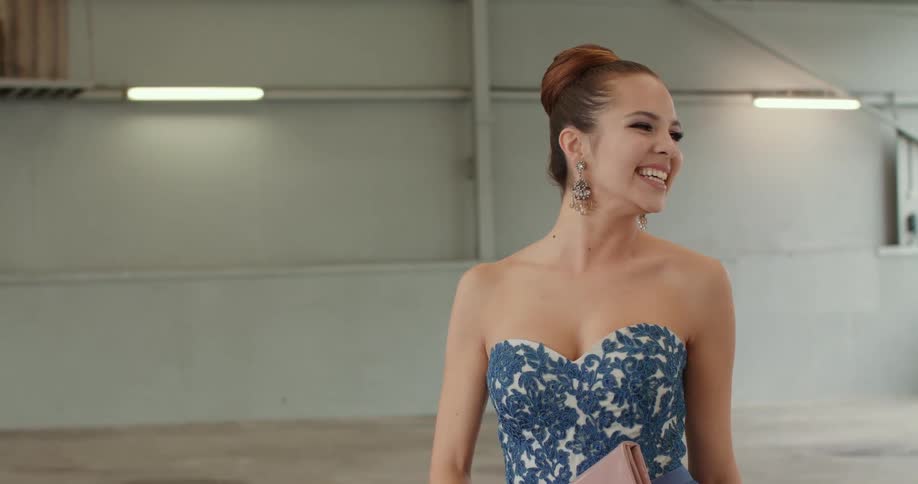 A woman is wearing a dress and smiling in an empty room