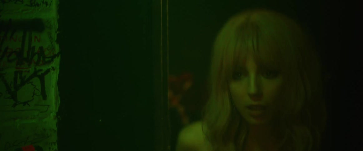 Young blonde woman enters a nightclub through the back door at night