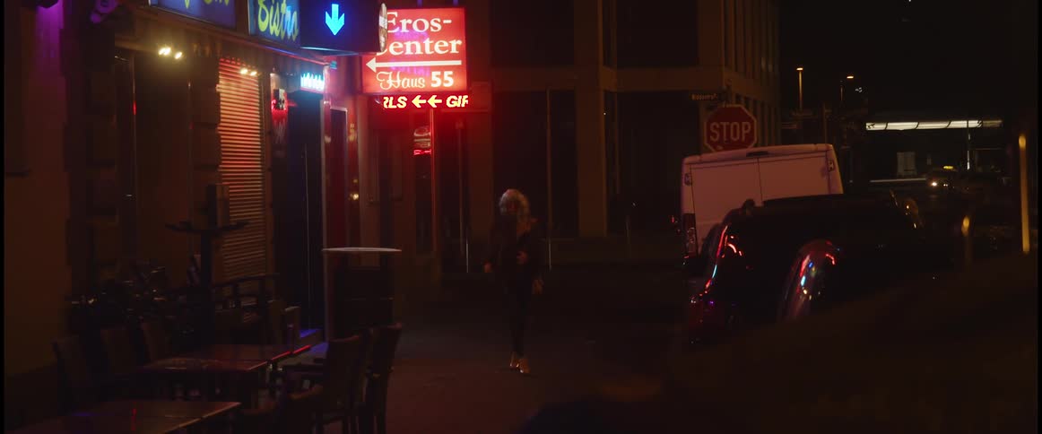 A woman walks away from a bar at night