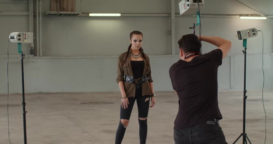 A model poses for a photographer in a studio