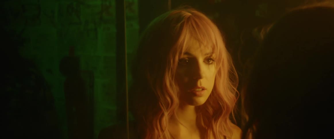 A woman walks up to a mirror and checks her hair and makeup