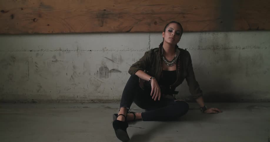 A woman poses as she sits on a floor