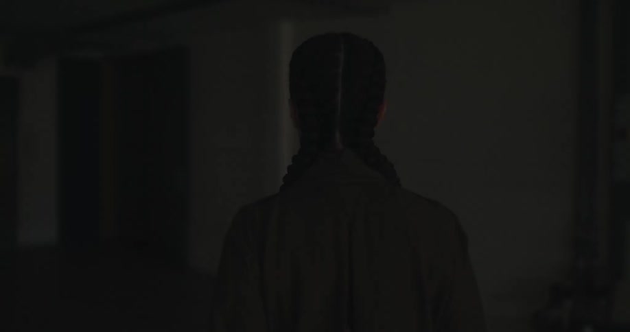Woman with twin pigtails walks on the dark rooms and hallways of an empty building