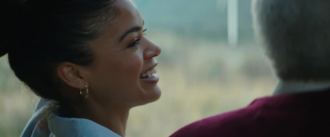 A woman feels the wind then waves and laughs