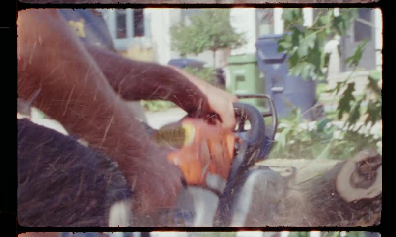 A man saws a tree trunk by his house
