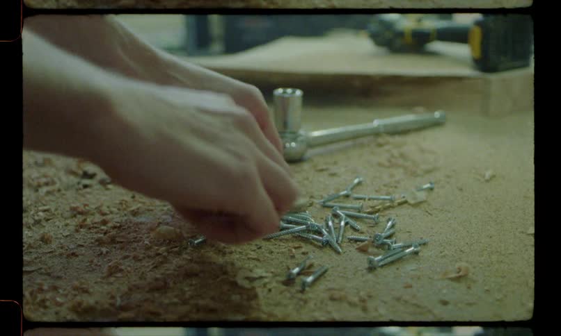 A carpenter wipes sawdust off from a table