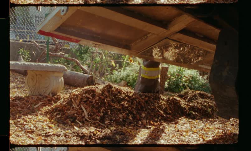 Sawdust falls into a pile on the floor as a carpenter works on a wooden table