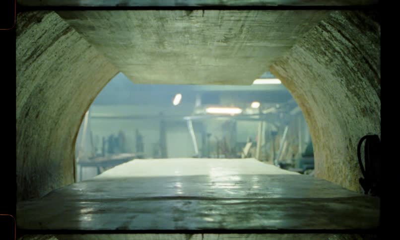 A piece of sheet metal moving into an arced oven in a workshop