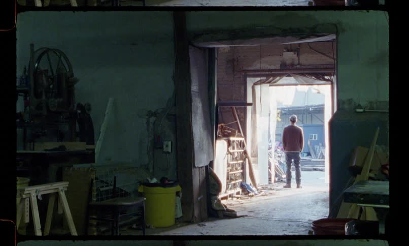 A man walks out of a workshop and looks around