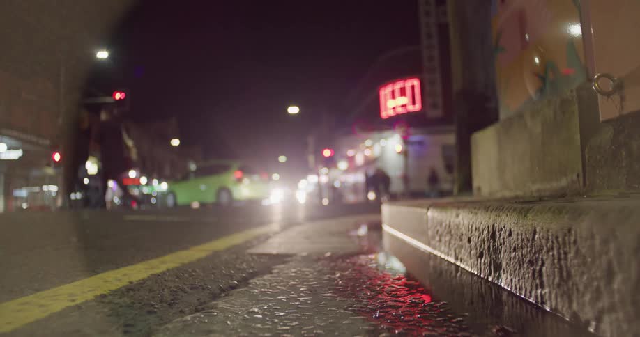 Pedestrians cross a city street as cars drive past