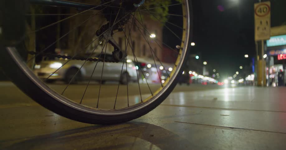 A bicycle is stopped on a city sidewalk as heavy traffic passes by